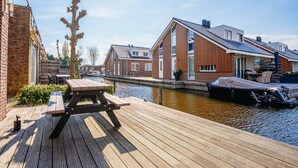 A wooden dock with a picnic table, a canal, and houses with modern architecture. - Waterside Escape With Easy Access (Uitgeest)