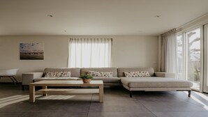 A modern living room with a sectional sofa, a coffee table, and a large window with curtains. - Waterside Escape With Easy Access (Uitgeest)