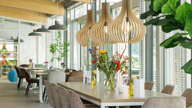 A modern dining area with a wooden table, cushioned chairs, and hanging wooden pendant lights. - Sunny Dunimar Retreat (Noordwijkerhout)