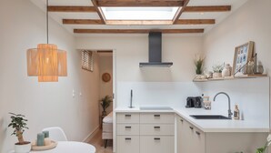 Een moderne keuken met dakraam, witte kasten, een centraal eiland en een hangende pendelarmatuur.