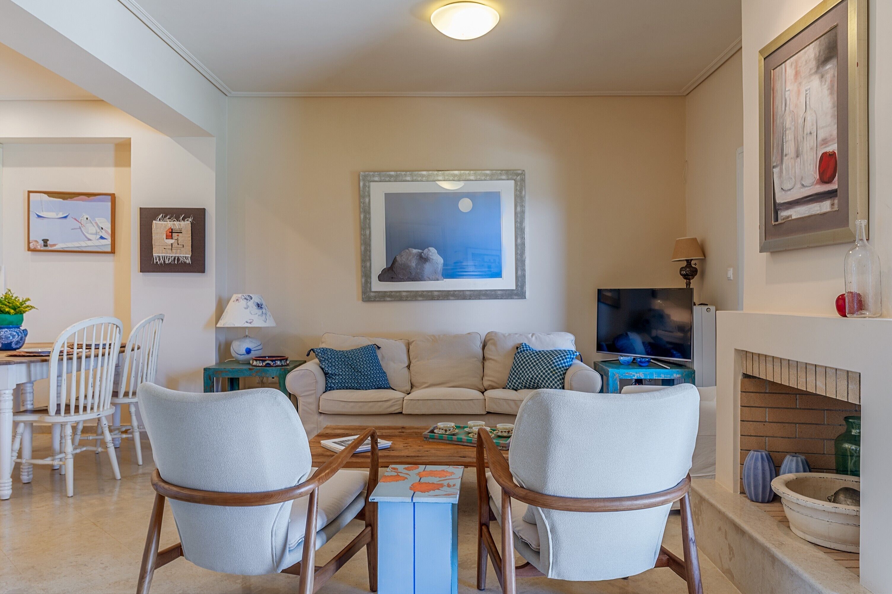 Una sala de estar con sofá, dos sillones, una mesa de centro, televisor y chimenea.