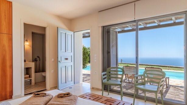 Une chambre d’hôtel avec un lit, une salle de bain et un balcon donnant sur la mer.