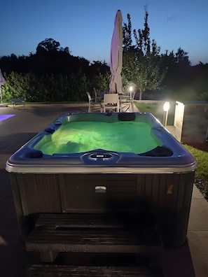 A hot tub with a cover, surrounded by outdoor furniture and a patio area.