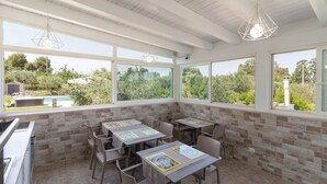 Une terrasse ensoleillée avec des sièges d’extérieur, un mur de briques et une vue sur la verdure.