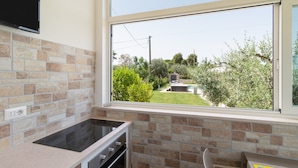 A kitchen with a large window, a built-in oven, and a stone backsplash. - Corallo House - Alba Rossa Room with Shared Pool, Wi-Fi and Air Conditioning (Polignano a Mare)