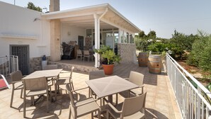 An outdoor patio with tables and chairs, a covered seating area, and a potted plant. - Corallo House - Alba Rossa Room with Shared Pool, Wi-Fi and Air Conditioning (Polignano a Mare)