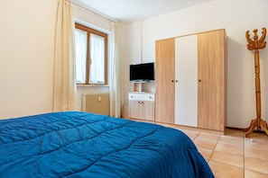 A bedroom with a bed, a wardrobe, a television, and a wooden trident. - Apartment 'Appartamento Vioz' with Mountain View and Balcony (Peio)