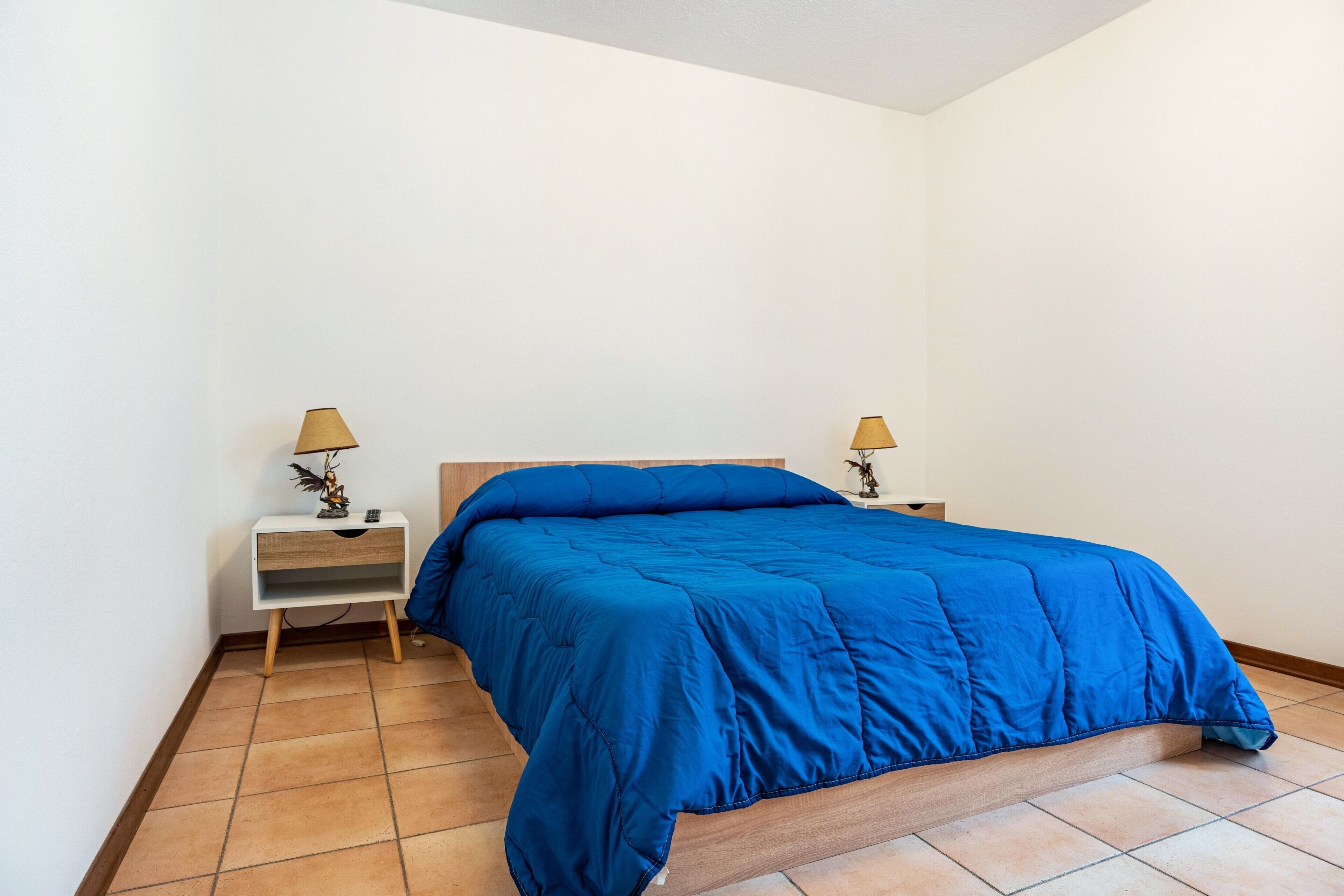 A bedroom with a bed, two bedside tables, and a nightstand.