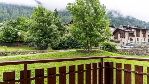 A wooden balcony with a view of a mountain village, stone buildings, and a pathway. - Apartment 'Appartamento Vioz' with Mountain View and Balcony (Peio)