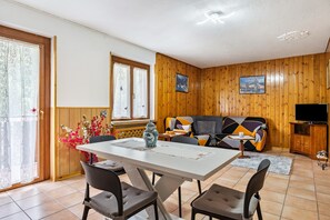 Une pièce avec un mur lambrissé en bois, un canapé, un téléviseur et une table à manger avec des chaises.
