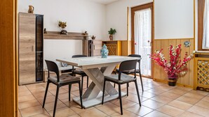 A dining area with a table, chairs, a cabinet, and a potted plant. - Apartment 'Appartamento Vioz' with Mountain View and Balcony (Peio)