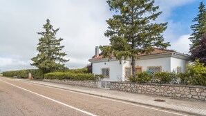 Ein zweistöckiges weißes Gebäude mit roten Ziegeln auf dem Dach, einer Steinwand und einem gepflasterten Bürgersteig.