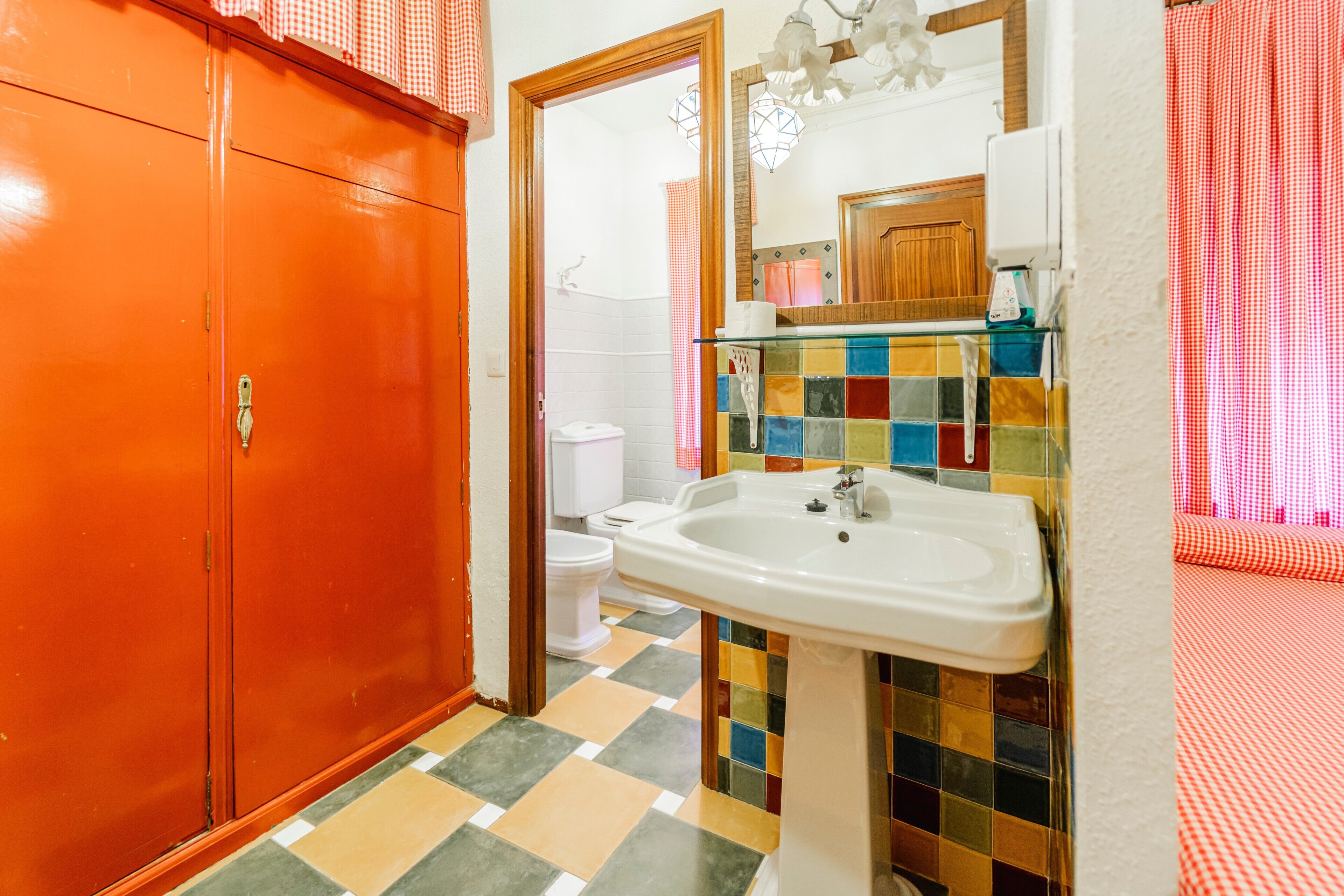 Un baño con piso de baldosas, un lavamanos, un inodoro y un espejo.