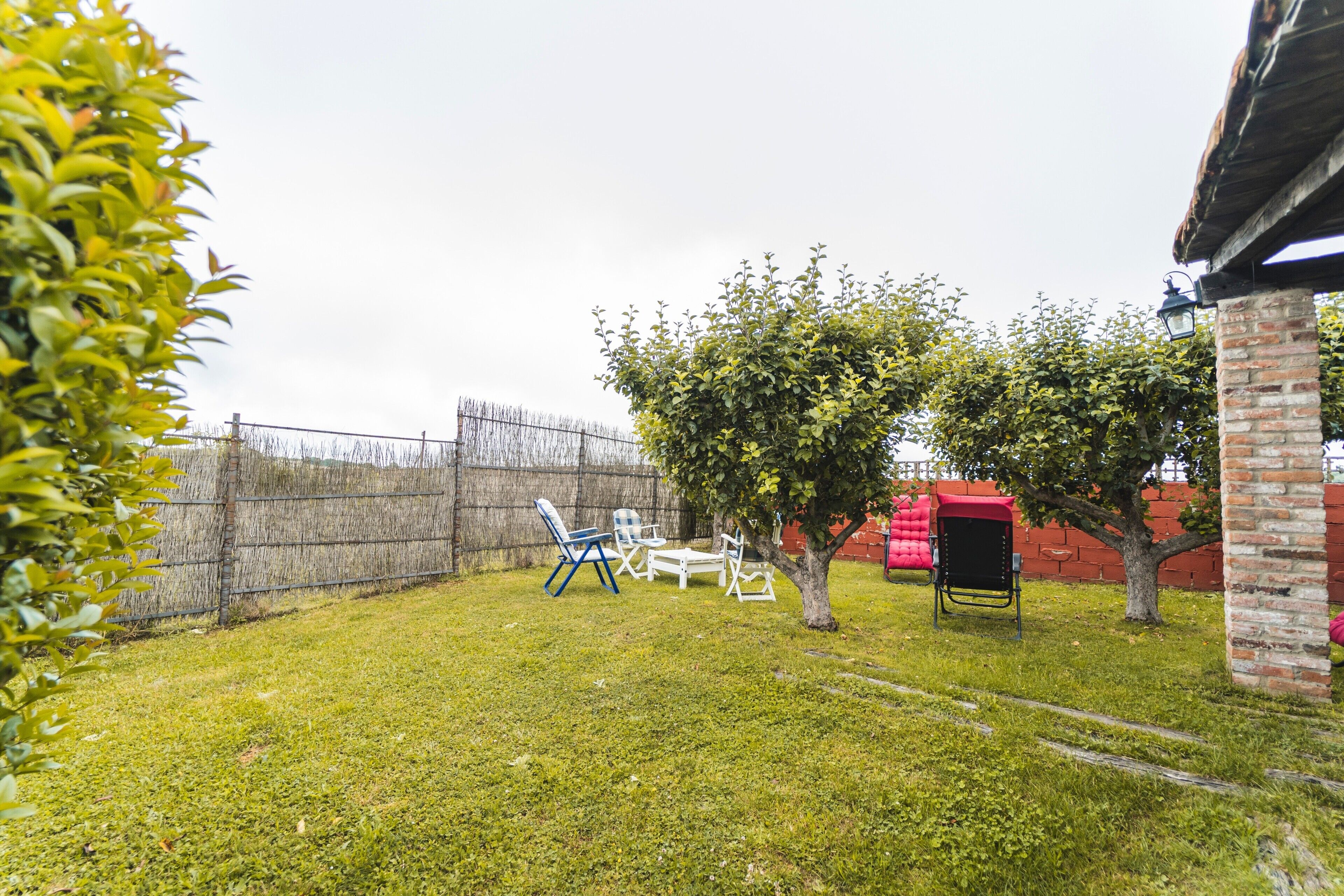 Ein Garten mit Rasenfläche, einer Backsteinmauer und einer roten Struktur.