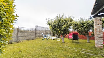 Ein Garten mit Rasenfläche, einer Backsteinmauer und einer roten Struktur.
