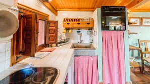 A kitchen with wooden cabinets, a sink, a stove, and a hanging rack with dishes. - Country House 'El Gallinero' with Mountain View and Private Garden (Castrejón de la Peña)