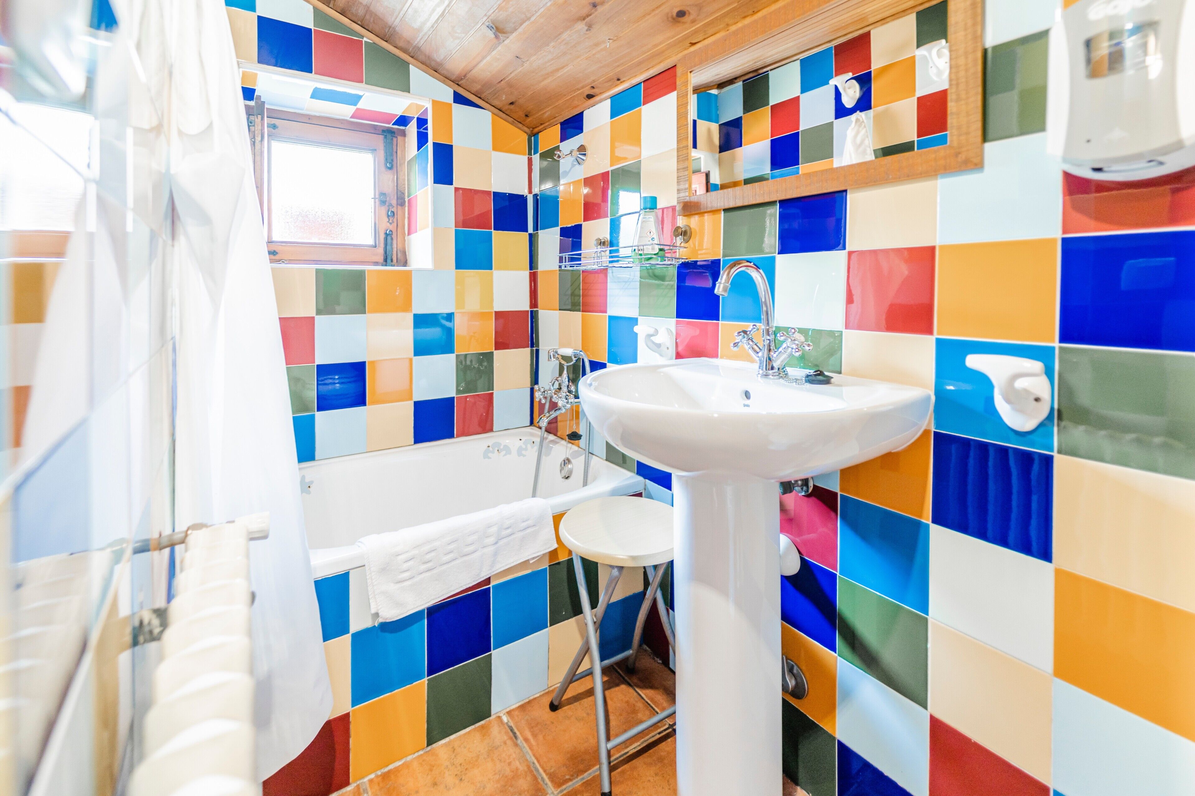 Un bagno con piastrelle colorate, un lavandino, una vasca e una finestra.