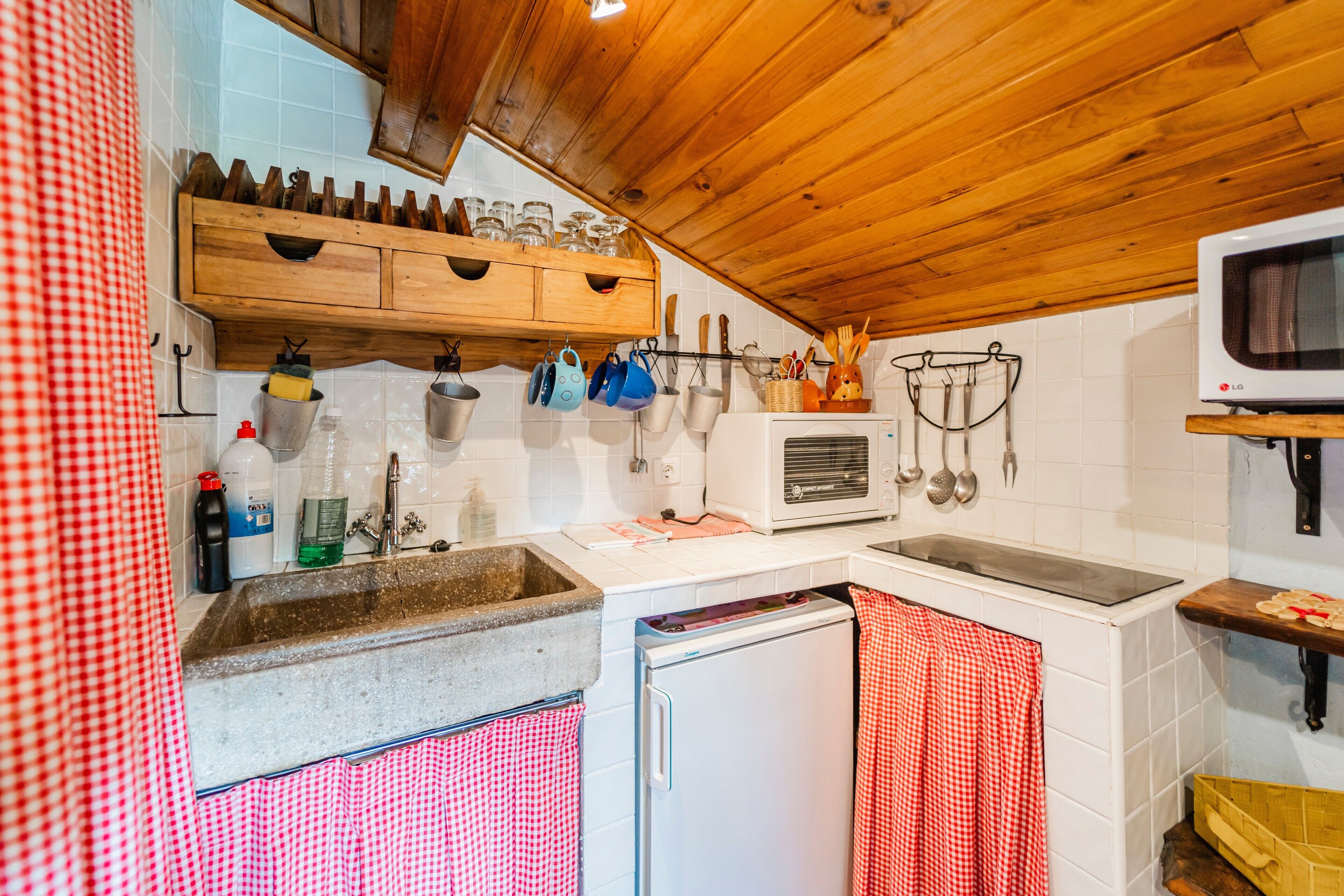 Una cocina con armarios de madera, microondas, pileta y refrigerador.