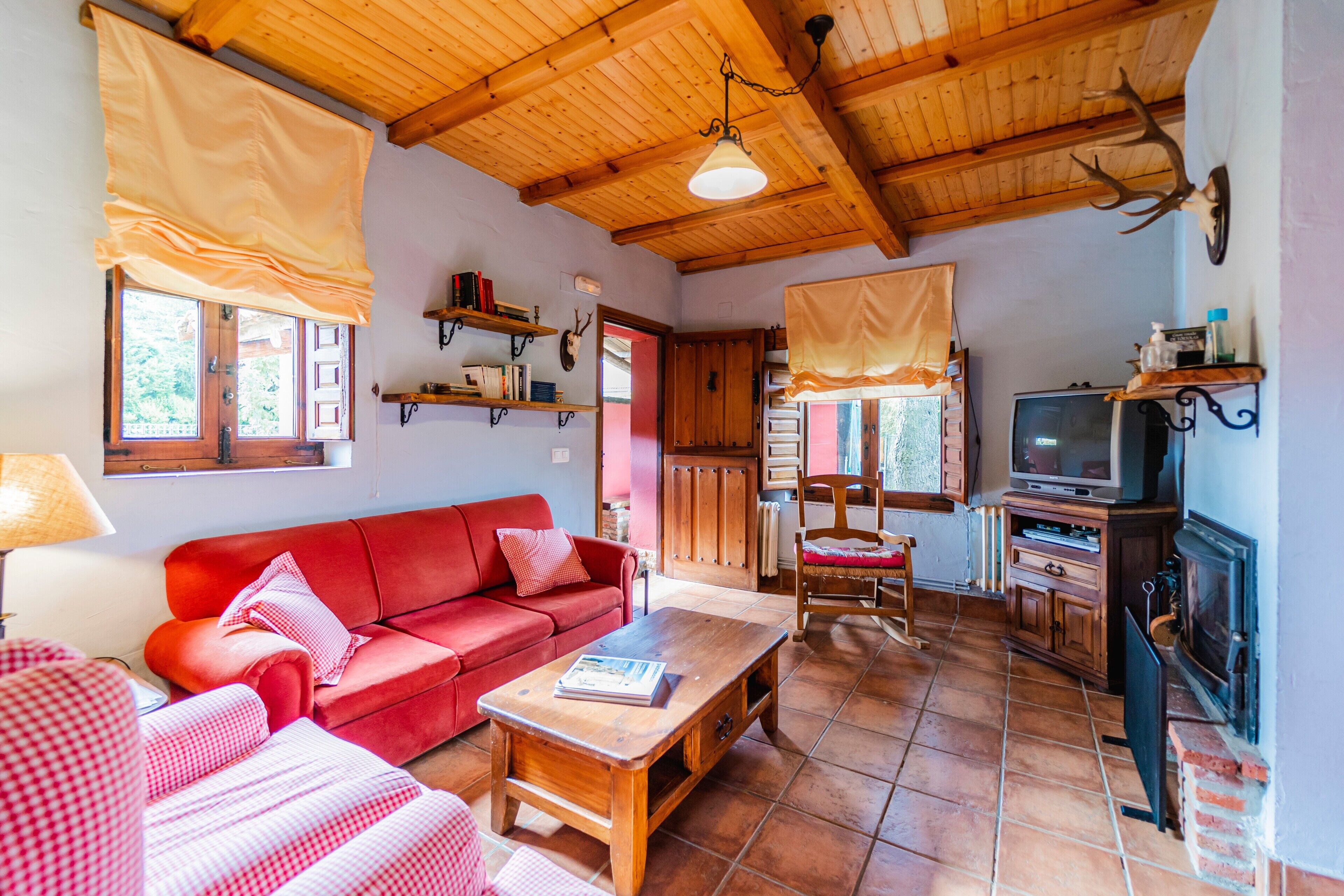 Ein gemütliches Wohnzimmer mit einem roten Sofa, einem Holztisch und einem Kamin.