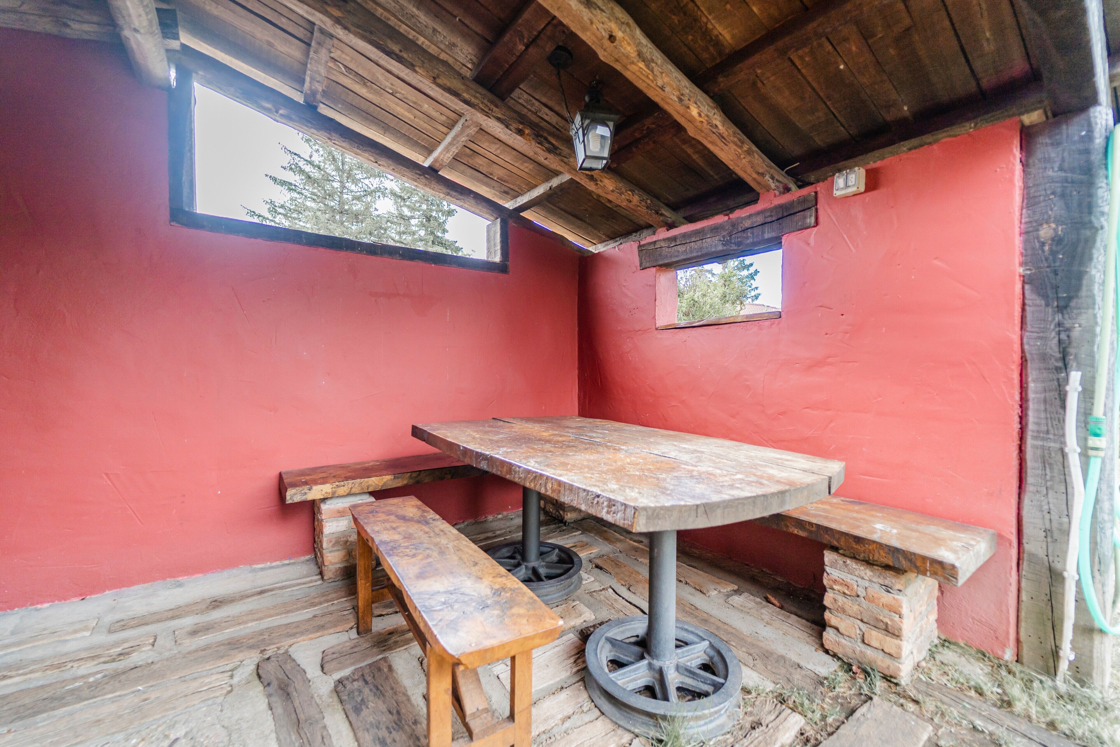 Um quarto rústico com uma mesa de madeira, bancos e uma janela.