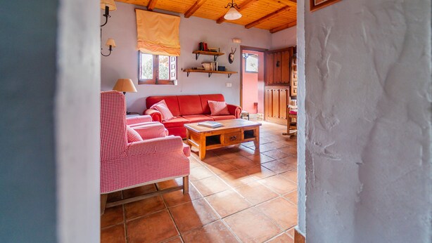 Una sala de estar con un sofá rojo, una silla a cuadros y una mesa de centro de madera.