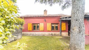 Un edificio rojo con contraventanas amarillas, una chimenea de ladrillo y un patio cubierto de césped.