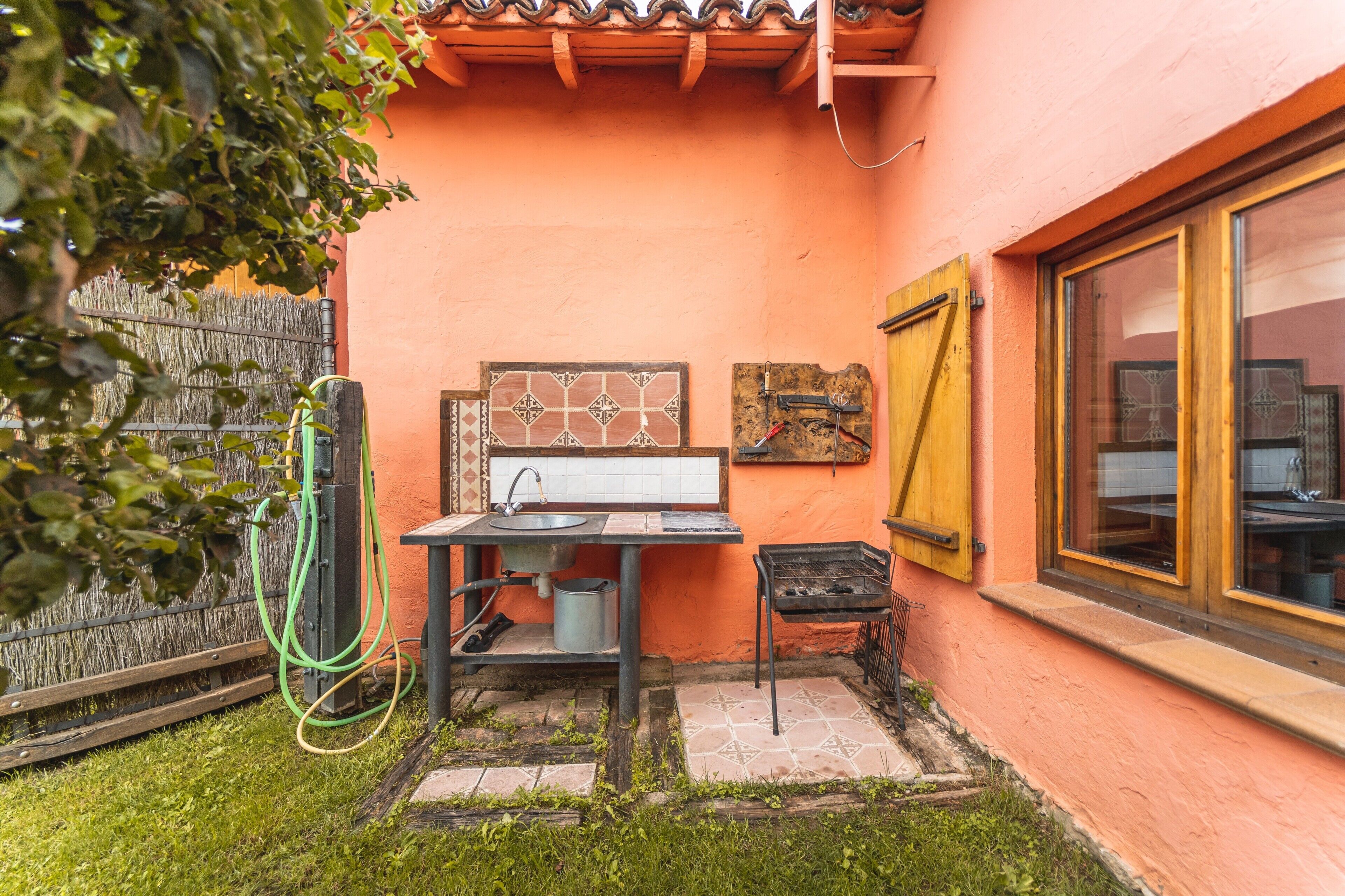 Un pequeño espacio de cocina al aire libre con pileta, parrilla y ventana.