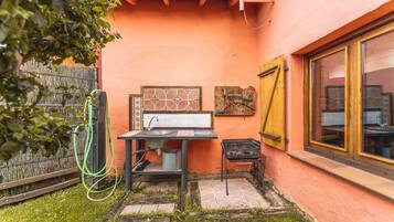 Un pequeño espacio de cocina al aire libre con pileta, parrilla y ventana.