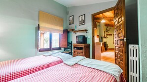 Una camera da letto con due letti, una televisione, un armadio in legno e un termosifone.