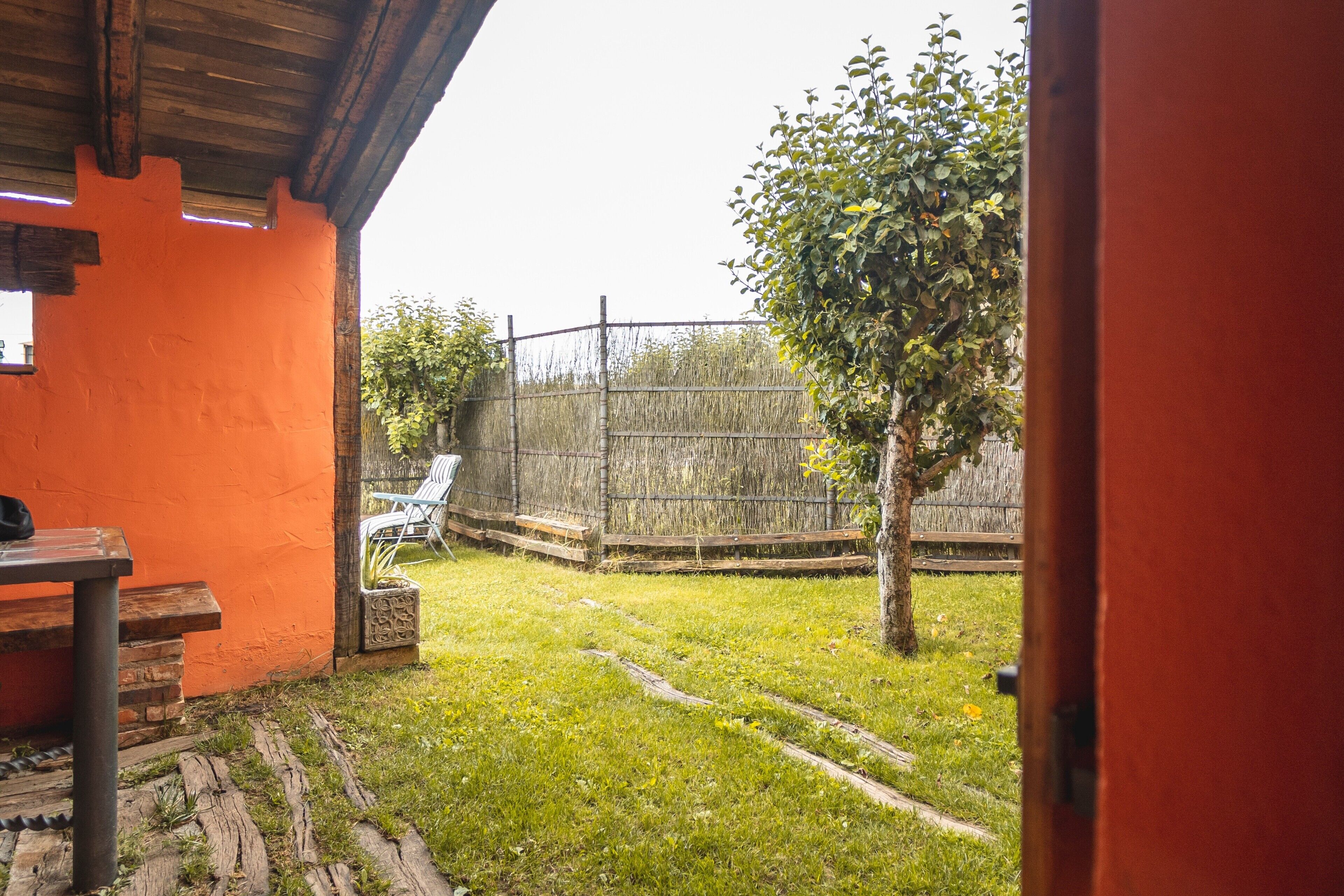 An outdoor area with a wooden fence, a tree, and a table with chairs.