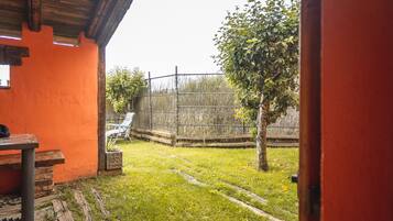 An outdoor area with a wooden fence, a tree, and a table with chairs.