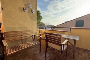 A patio with wooden benches and a table, a wall with decorative plates, and a view of buildings in the background. - N290 - Numana, three-room apartment with terrace overlooking the sea (Numana)