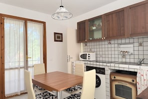 A kitchen with wooden cabinets, a microwave, a stove, and a dining area with a table and chairs.