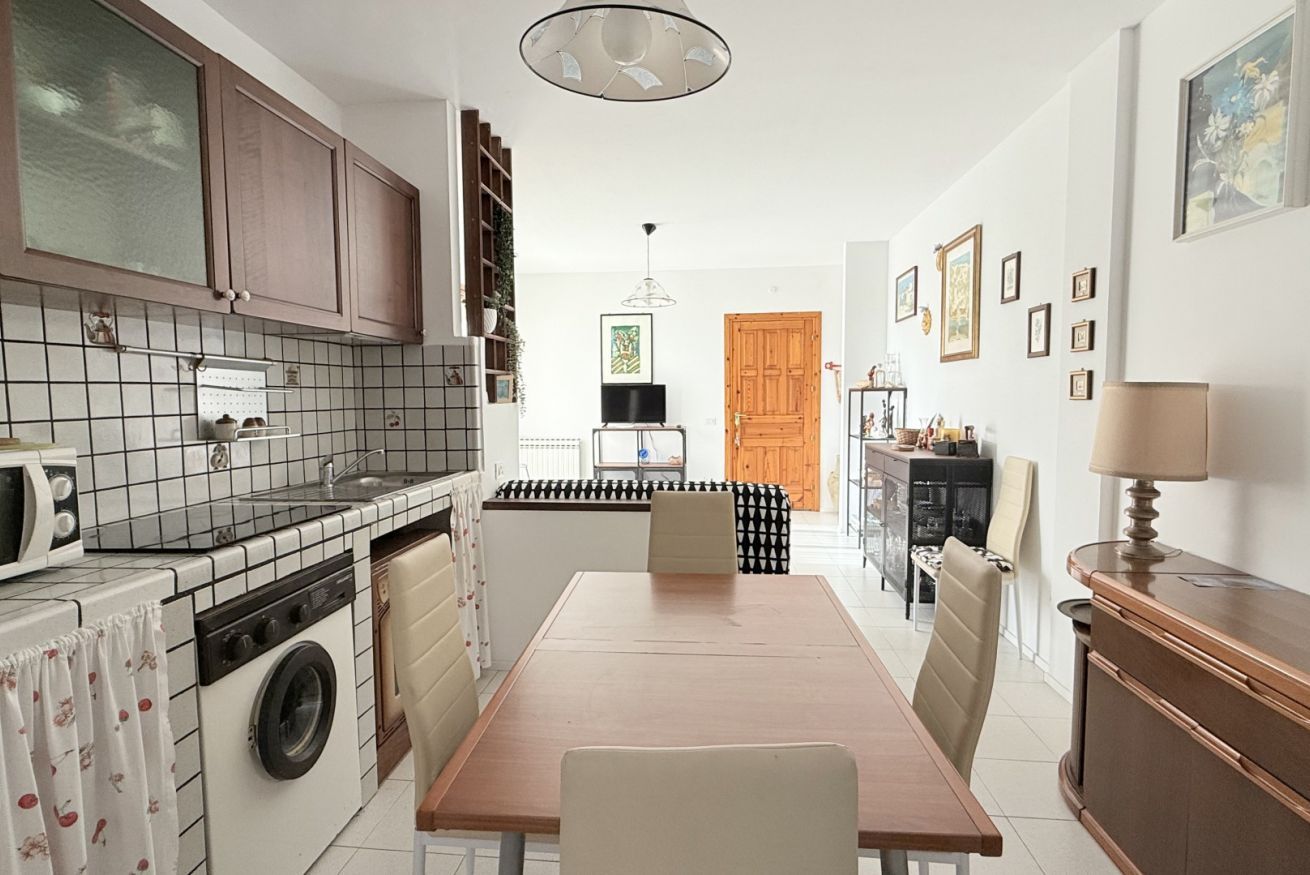 A compact kitchen with a washing machine, a dining table, and a wooden door.