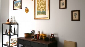 Quarto com estante de livros, quadros e escrivaninha com diversos objetos.