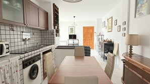 Uma cozinha compacta com máquina de lavar, mesa de jantar e porta de madeira.