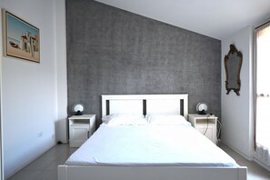 A bedroom with a large bed, two bedside tables, a mirror, and a painting on the wall. - N290 - Numana, three-room apartment with terrace overlooking the sea (Numana)
