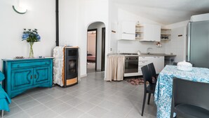 Une cuisine moderne avec des meubles blancs, une cuisinière noire et un coin repas comprenant une table et des chaises.
