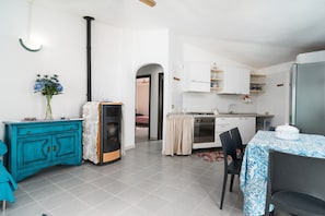 Una cocina moderna con gabinetes blancos, una estufa negra y un comedor con mesa y sillas.