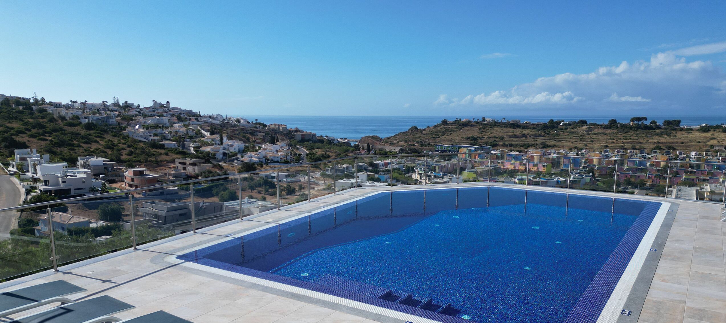 A rooftop pool with a clear view of the surrounding hillside and ocean.