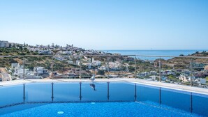 A pool with a clear view of a coastal town and the sea.