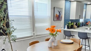 Ein Essbereich mit einem runden Tisch, sechs Stühlen und einer Vase mit orangefarbenen Blumen.