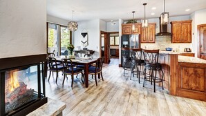 A spacious kitchen with wooden cabinets, a dining area with a fireplace, and a bar area with stools. - NEW The Hamilton Chalet: Private Hot Tub, Seclusion, & Incredible Mtn Views! (Breckenridge)