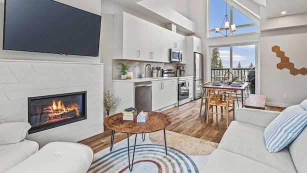 Una sala de estar moderna con chimenea, un televisor de pantalla plana y un comedor con vistas al exterior.