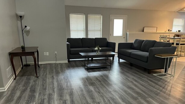 Una sala de estar con dos sofás, una mesa de centro y una mesita auxiliar.