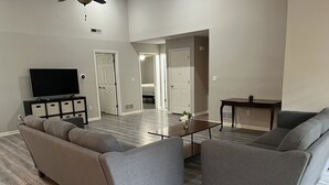 Una sala de estar moderna con un sofá seccional gris, una mesa de centro y un televisor sobre un mueble bajo.
