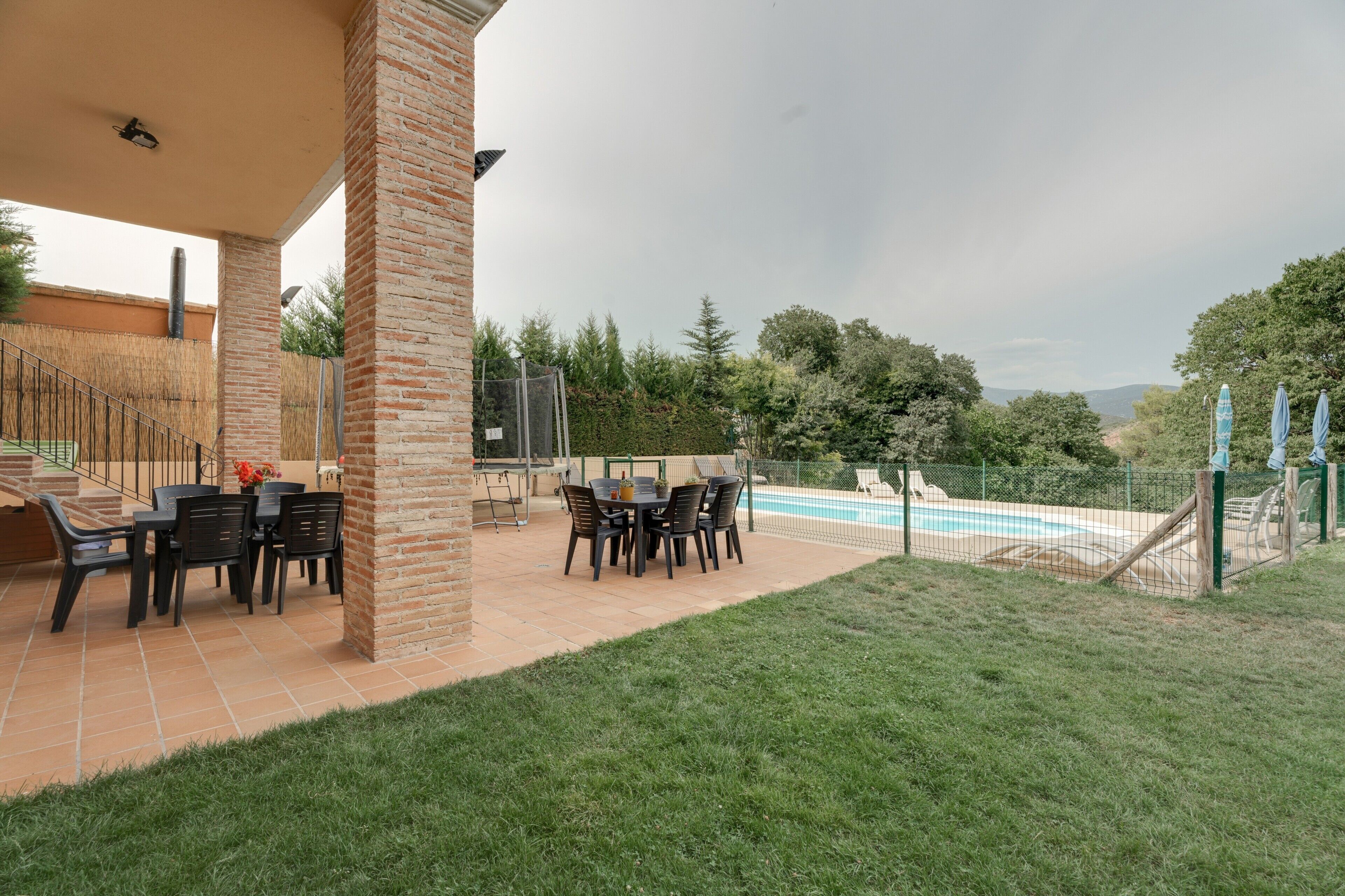 Un patio al aire libre con piscina, rodeado de un muro de ladrillo y una valla.
