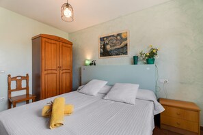 Ein Schlafzimmer mit einem Bett, einem Holzschrank, einem Bild an der Wand und einem Nachttisch mit einer Lampe.