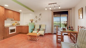 A spacious living area with a kitchen, dining table, and chairs, a sofa, and a balcony with a view. - Holiday Home 'Sueños De Guara Casa Rural' with Mountain Views, Private Pool and Wi-Fi (Casbas de Huesca)