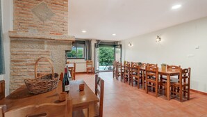 A dining area with brick walls, wooden tables and chairs, and a view through a glass door. - Holiday Home 'Sueños De Guara Casa Rural' with Mountain Views, Private Pool and Wi-Fi (Casbas de Huesca)